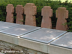 Five stone crosses next to the plaques bearing the names of soldiers buried in the Communal Grave.